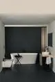 Badezimmeransicht mit freistehender Badewanne, Waschbecken und Wandarmaturen in Silk Black von Ideal Standard. Dunkle Wände und helle Einrichtung sorgen für einen modernen Look.